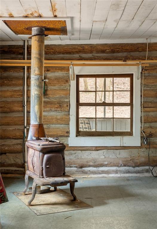 Rustic cabin interior with a cast-iron wood stove beside a divided-pane window.