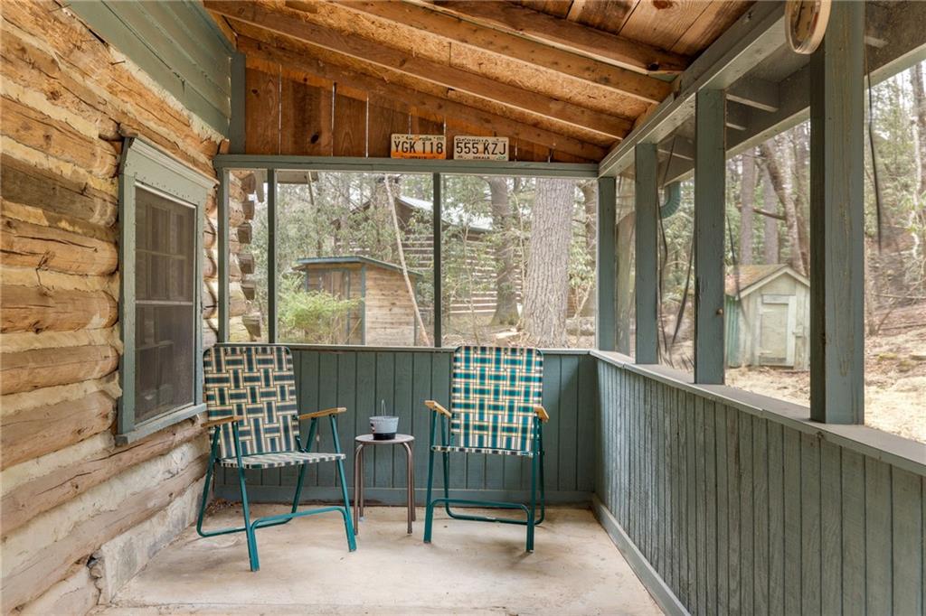 Screened porch with two woven chairs and a wooded view.