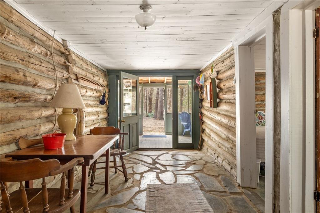 Rustic log cabin entry hall with stone flooring and glass doors opening to the woods.