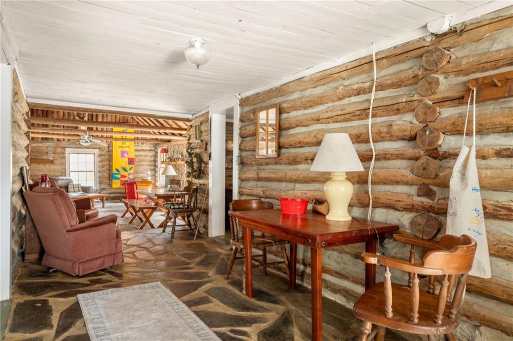 Rustic log cabin living room with flagstone flooring, armchairs, and wooden furniture.