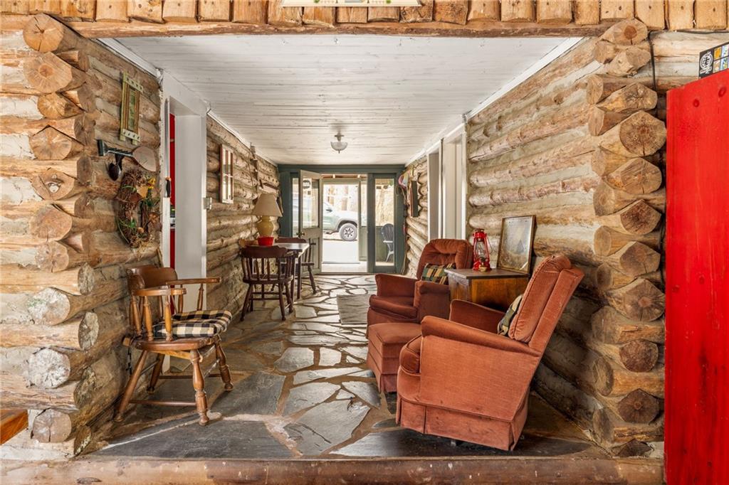 Rustic log cabin sitting area with leather armchairs, log walls, and a stone floor.