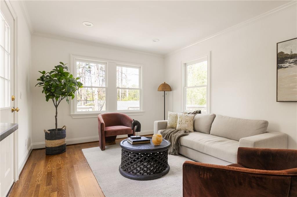 Living room with a light sofa, rust-colored armchairs, hardwood floors, and large windows.