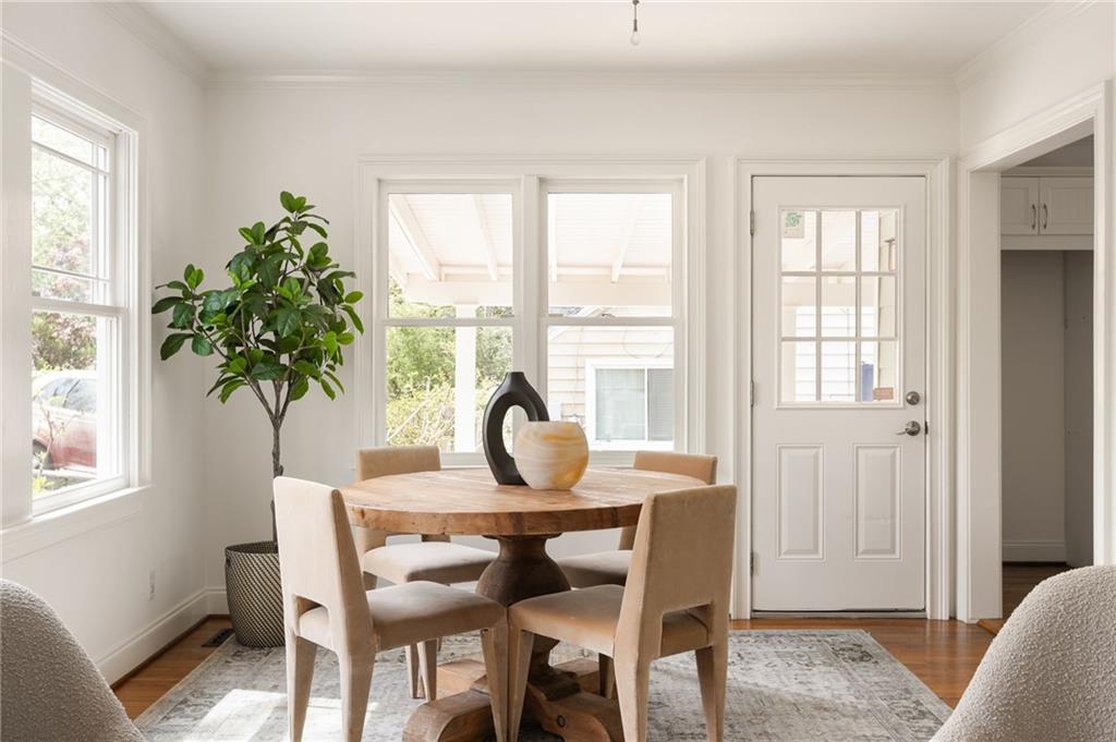 Dining room with a round wooden table, upholstered chairs, and large windows.