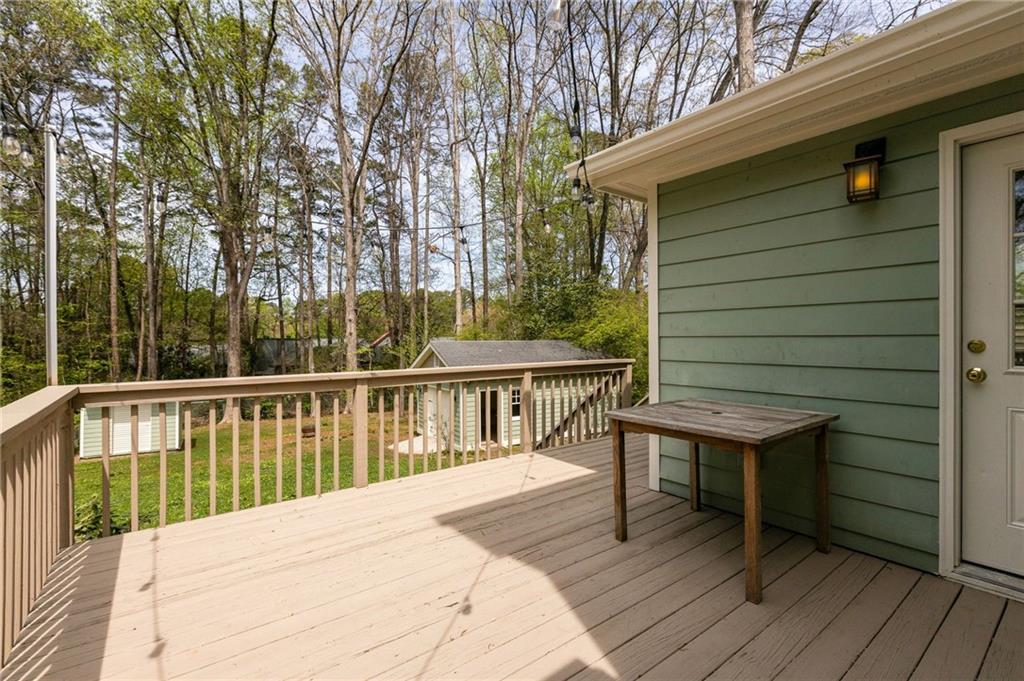 Raised wood deck overlooking a grassy, tree-filled backyard, with a small table beside the home.