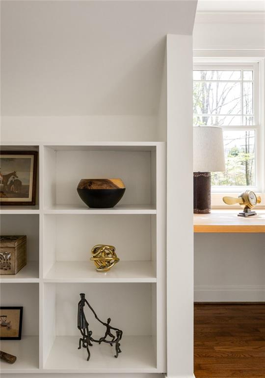 White built-in display shelves with decorative objects beside a bright window and hardwood floor.