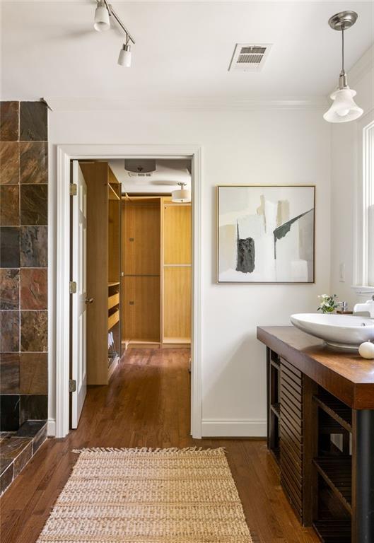 Bathroom with a wood vanity and vessel sink beside an open doorway to a wood-paneled closet.