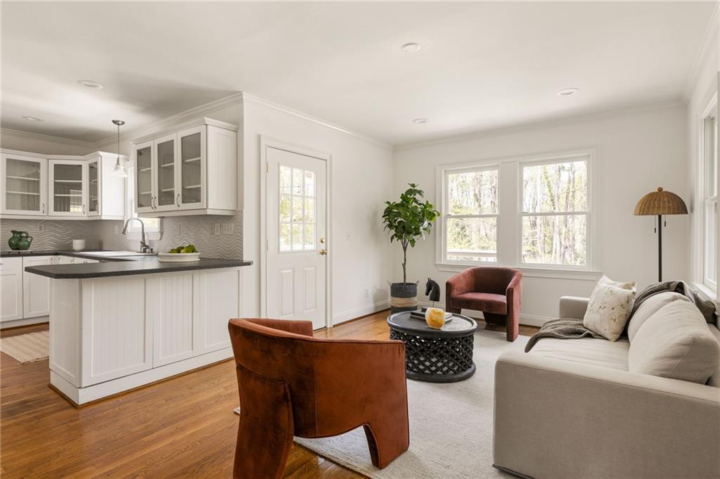 Open-plan living room and kitchen with a white island, large windows, and hardwood floors.