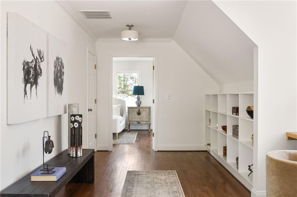 Furnished hallway with hardwood floors, built-in cubby shelves, and an open doorway to a bedroom.