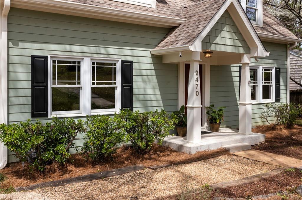 Home entry with sage-green siding, white columns, black shutters, and house number 2470.