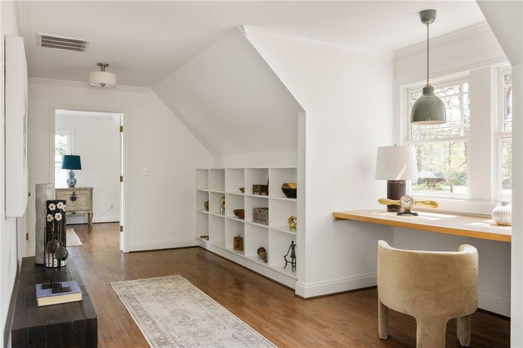 Bright home office with built-in cubbies and a desk beneath tall windows.