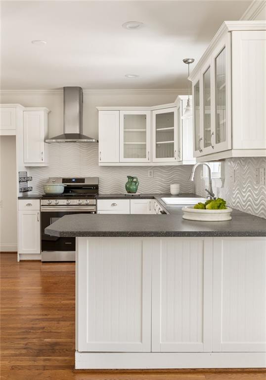 Kitchen with white cabinets, a gray island, stainless-steel range, and wavy backsplash.