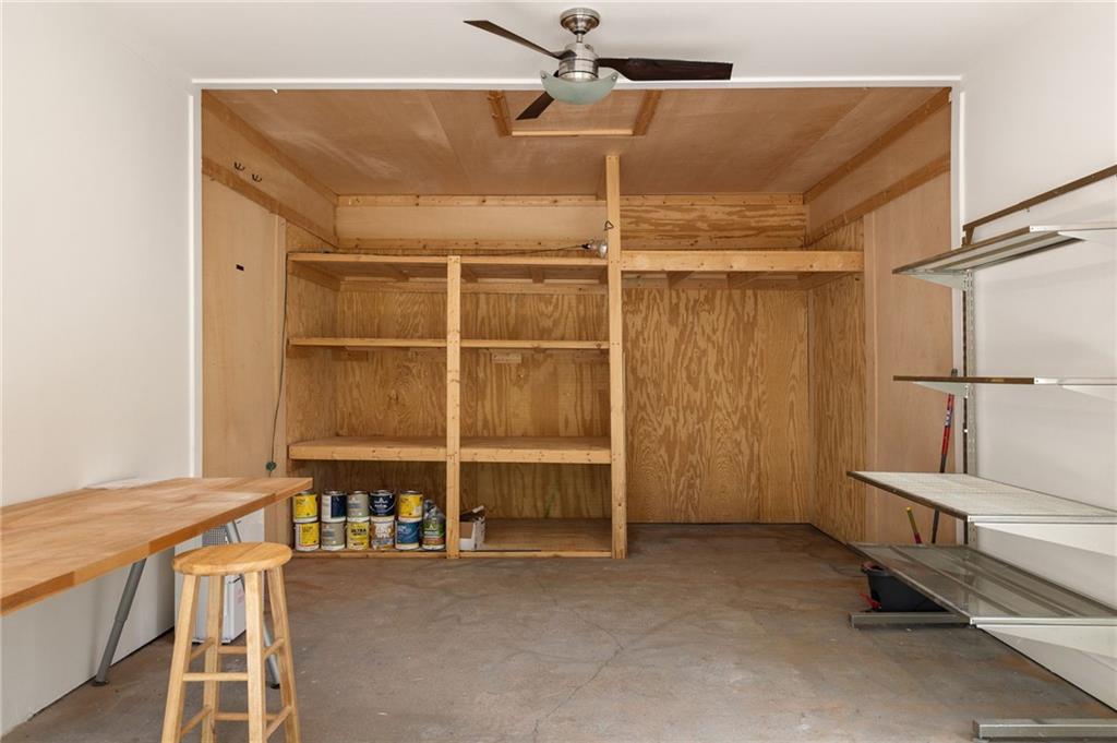 Garage with plywood shelving, a workbench, and metal storage racks.