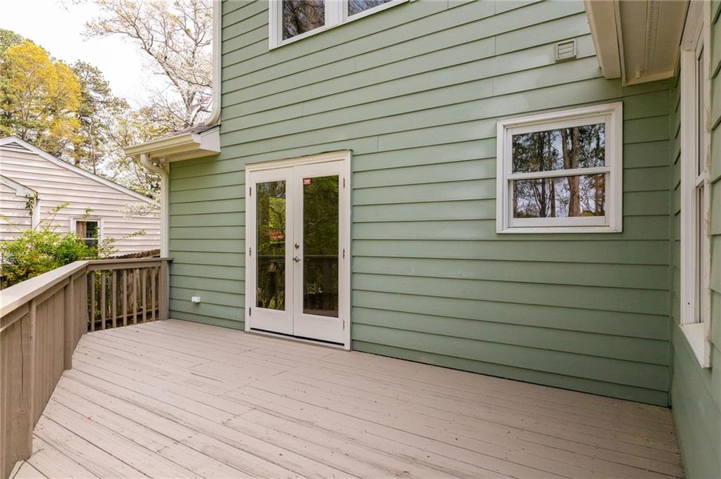 Raised deck with wooden railing, white French doors, and sage-green siding.