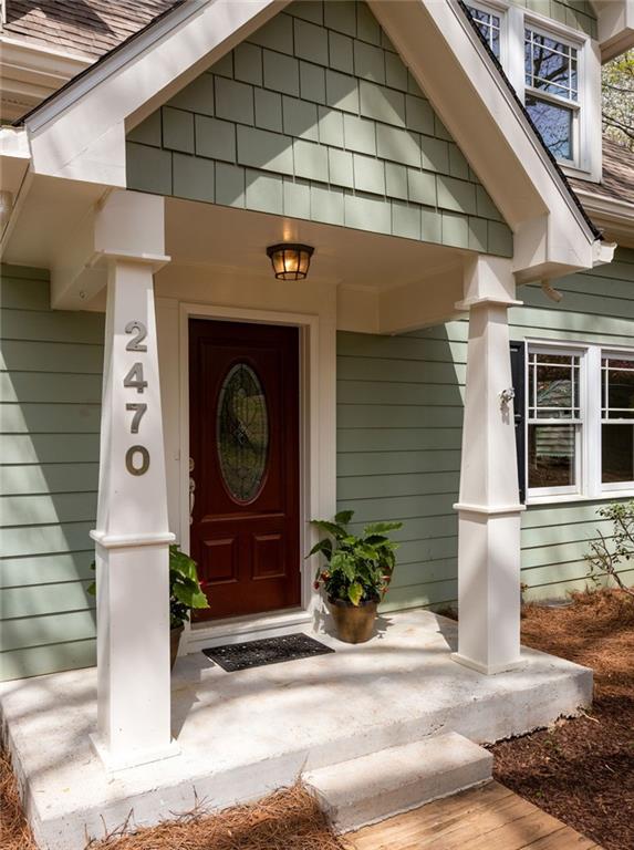 House entrance with a red glass-paneled door, white porch columns, and 2470 displayed on a column.