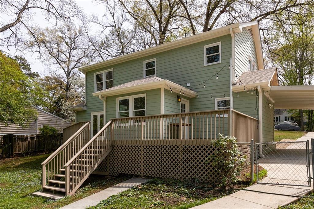 Rear of a green two-story house with a raised deck, long staircase, and string lights.