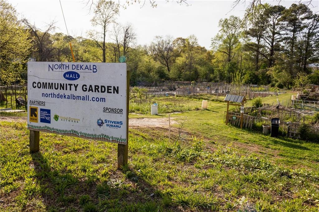 North DeKalb Mall community garden sign beside garden plots and paths.