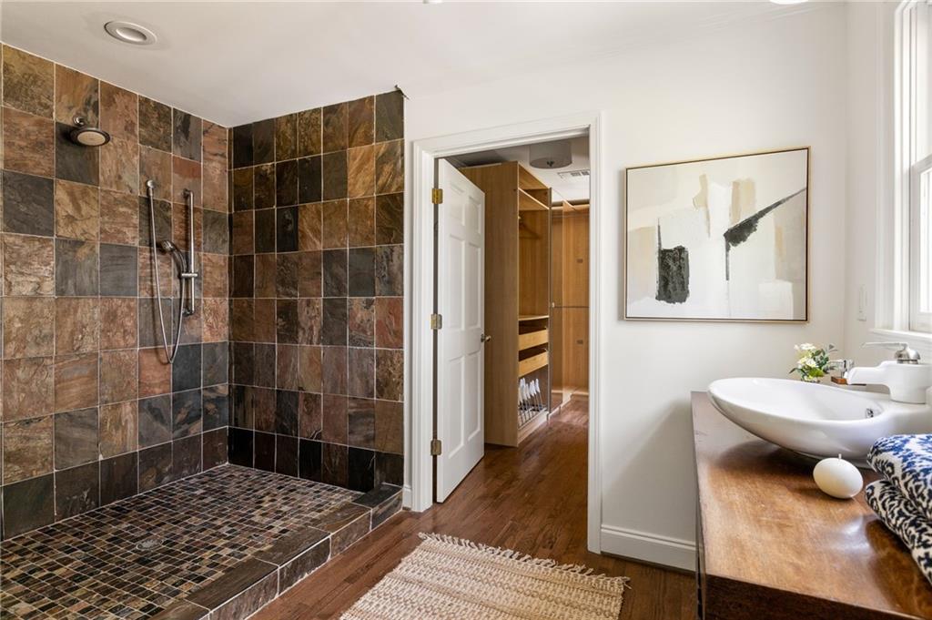Bathroom with a multicolored stone-tile walk-in shower and a wood-countertop vanity.