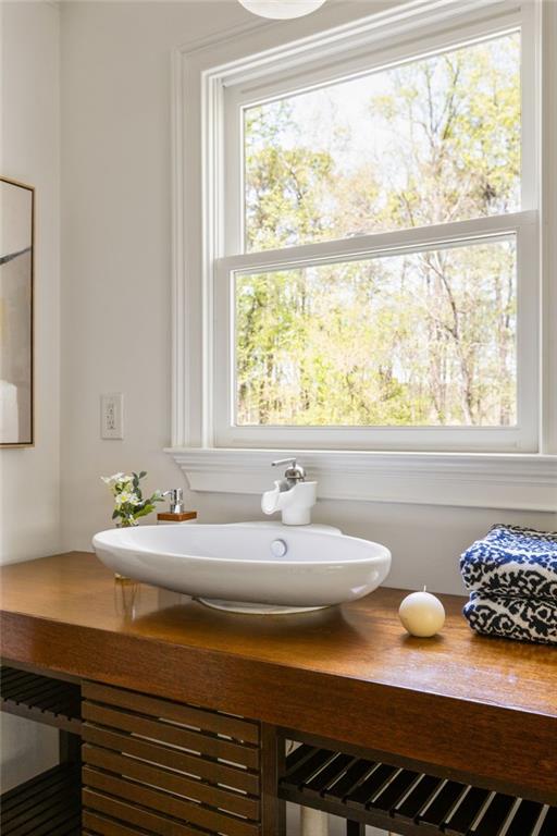 Bathroom vanity with a white vessel sink, wood countertop, and large window overlooking trees.