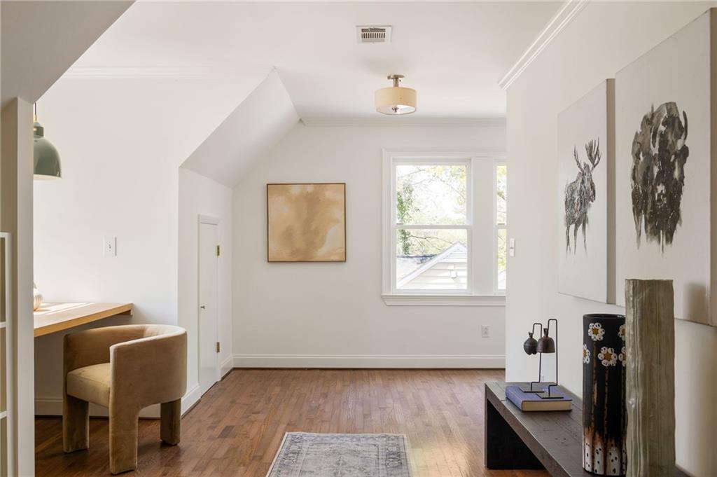 Bright room with hardwood floors, a window, and a desk beside a decorated console.