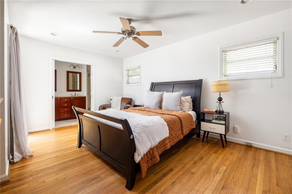 Bedroom with dark wood bed and rust-colored quilt, hardwood floors, and ensuite bathroom doorway.