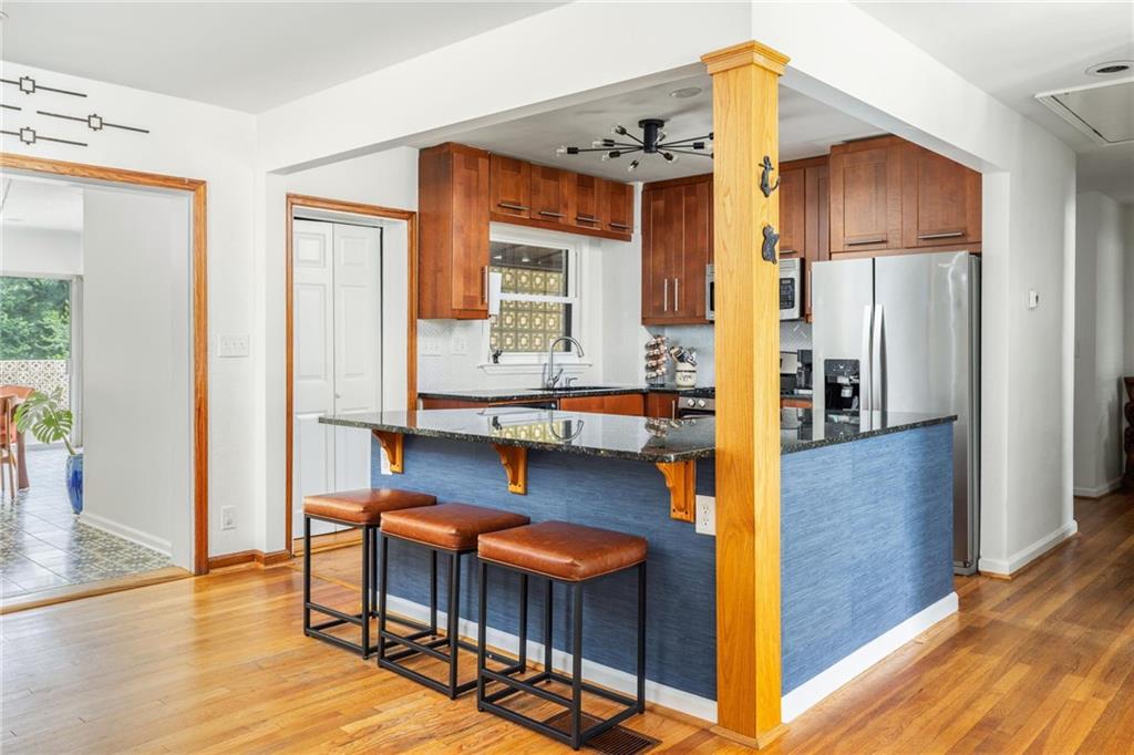 Kitchen with a blue island, three breakfast-bar stools, wood cabinets, and stainless steel appliances.