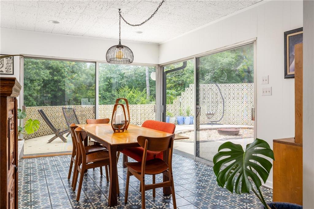 Dining room with patterned tile floors and glass doors opening onto a leafy patio.