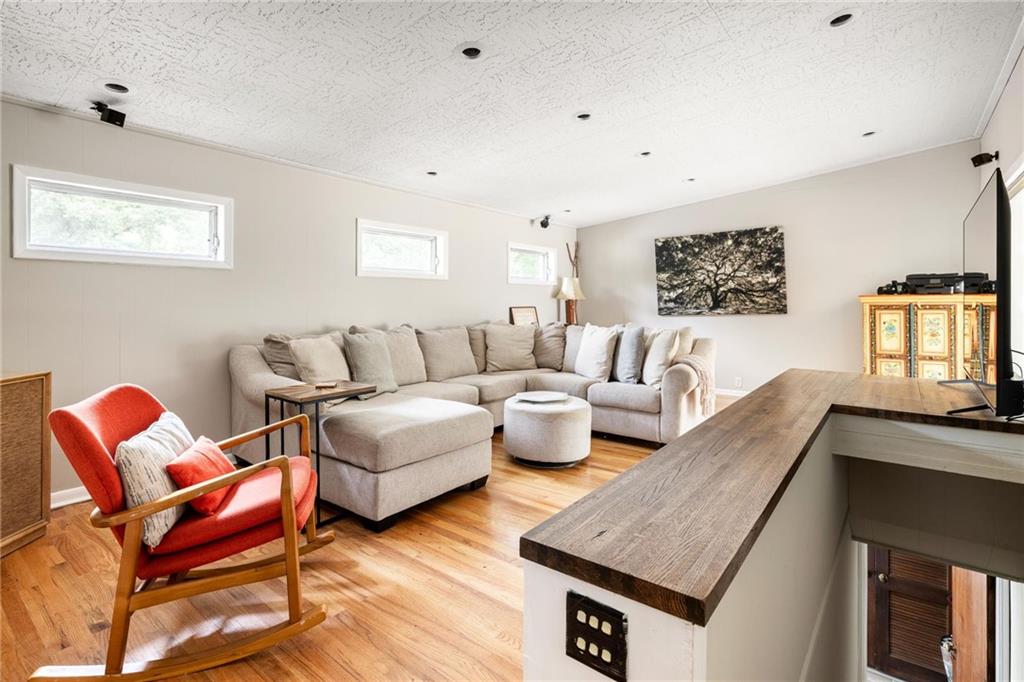 Living room with a beige sectional, red rocking chair, hardwood floors, and wood-topped counter.