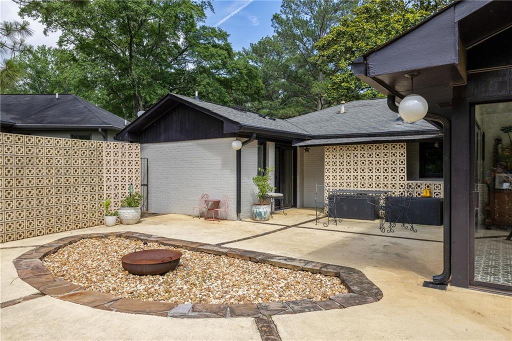 Rear courtyard patio with a gravel fire pit and patterned privacy walls.