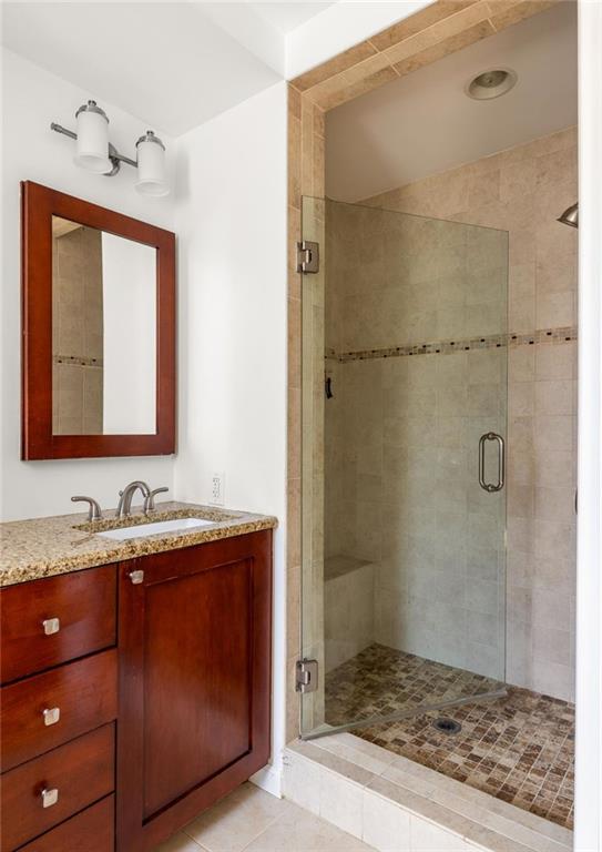 Bathroom with a dark wood vanity and a glass-enclosed tiled walk-in shower.