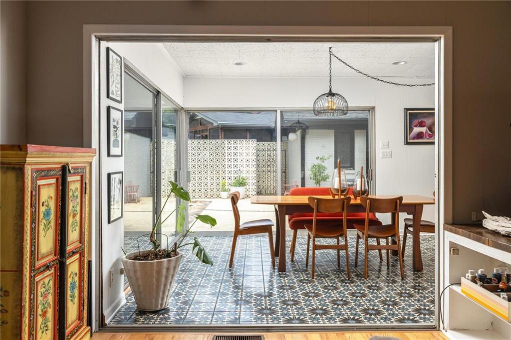 Dining room with patterned tile floors, a wooden table, and glass doors opening to a courtyard.