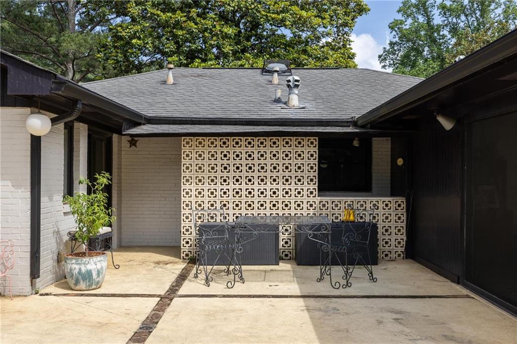 Courtyard patio with wrought-iron seating and a patterned breeze-block wall.