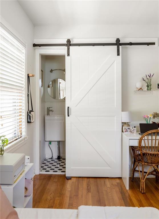 Bedroom with a white barn door opening to a bathroom and a small desk nook.