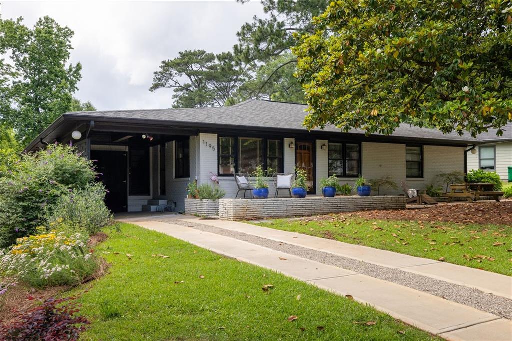 Single-story home with a covered porch, blue planters, and a walkway across the front lawn.