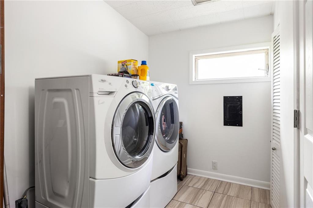 Laundry room with front-loading washer and dryer beneath a high window.
