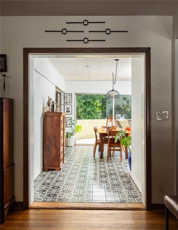 Dining room with patterned tile floors, a wooden table, and large windows overlooking greenery.