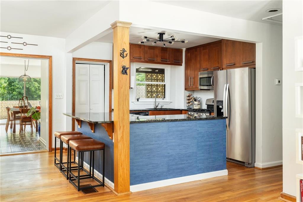 Kitchen with a blue island, wood cabinetry, stainless steel appliances, and hardwood floors.