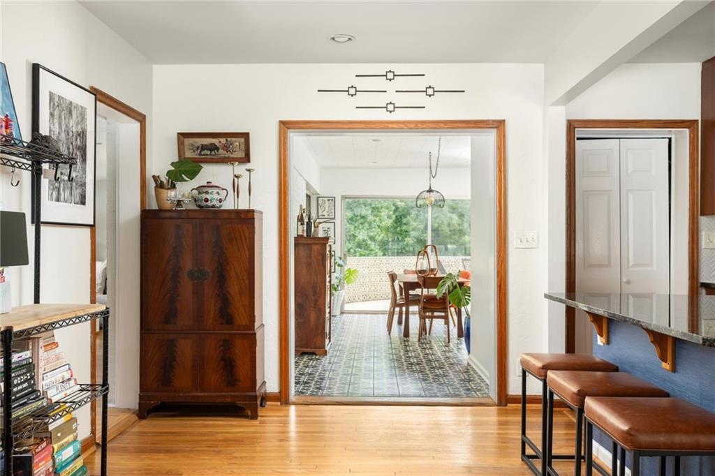 Furnished interior with hardwood floors, a breakfast bar, and a doorway to the dining area.