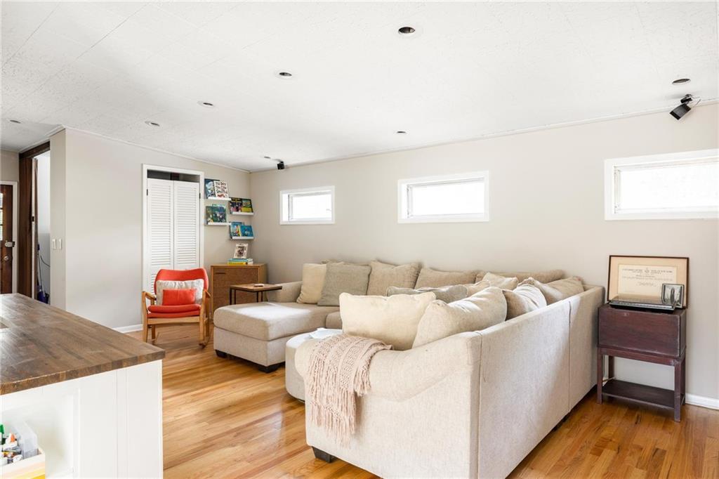 Furnished living room with a large sectional sofa, red accent chair, and hardwood floors.