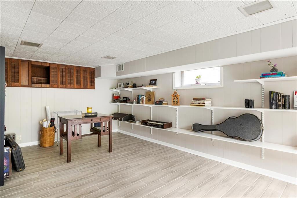 Basement room with long display shelves, wooden cabinets, tiled flooring, and a guitar case.