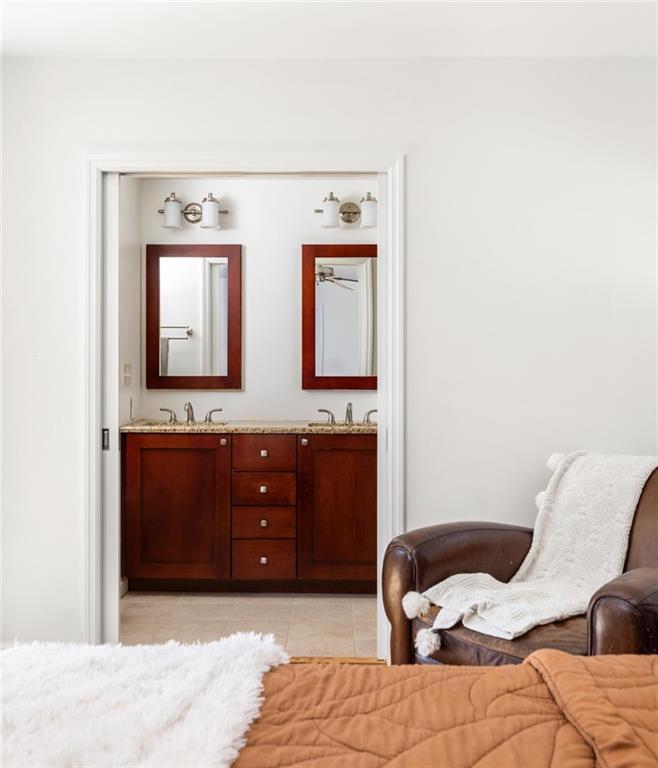 Bedroom with a rust-colored quilt and doorway opening to a double-sink bathroom.