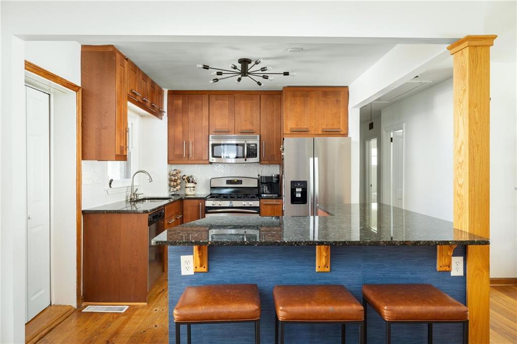 Kitchen with wood cabinets, stainless steel appliances, and a blue island with three leather stools.