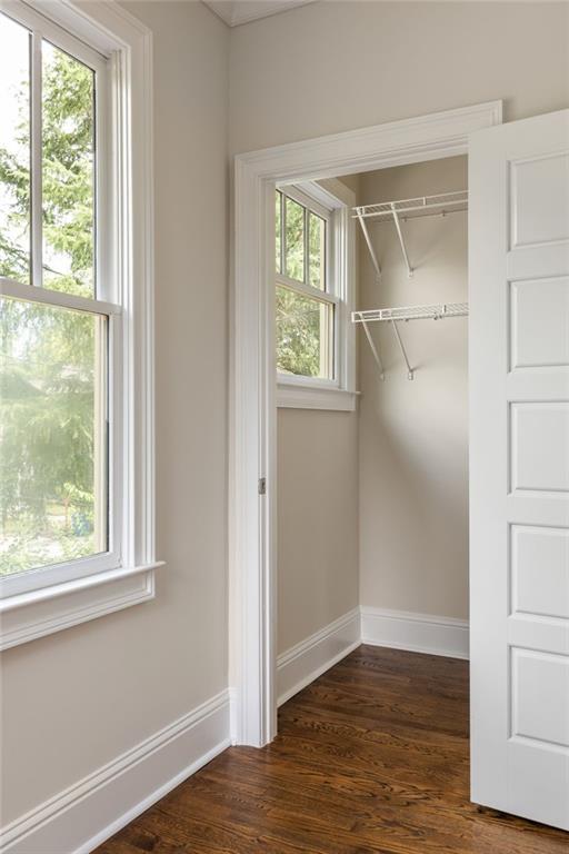 Empty closet with white wire shelves, a window, and dark hardwood floors.