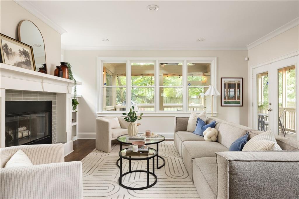 Furnished living room with a fireplace, large windows, and glass doors to a porch.
