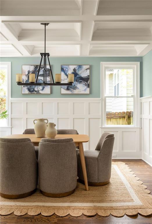 Dining room with a coffered ceiling, white paneled walls, and upholstered chairs around a wooden table.