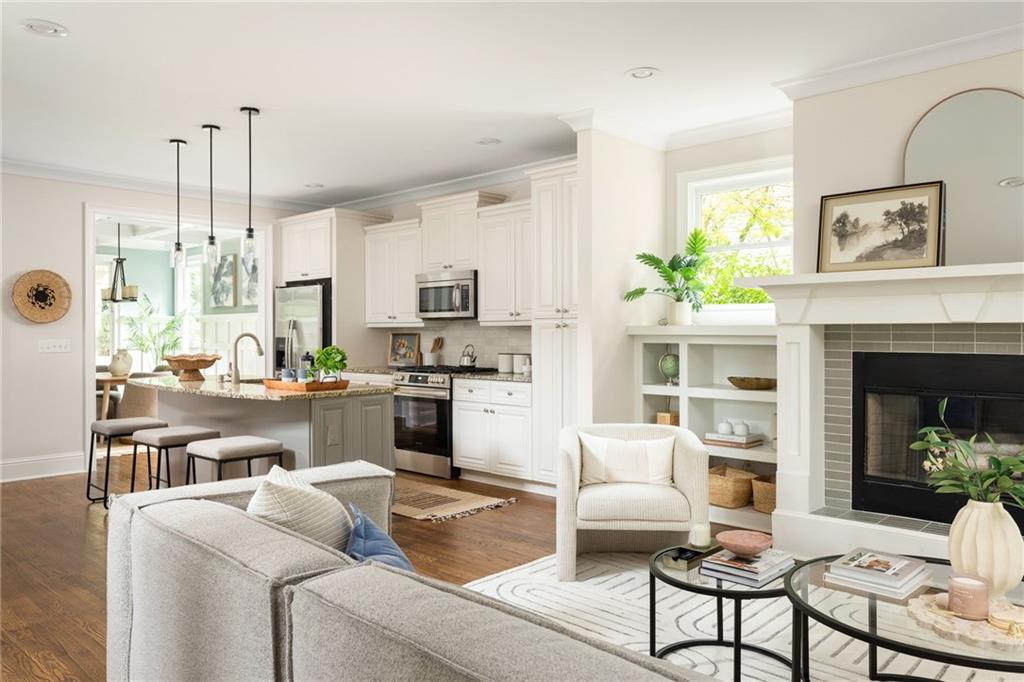 Open-plan living room and kitchen with white cabinetry, a fireplace, and neutral seating.