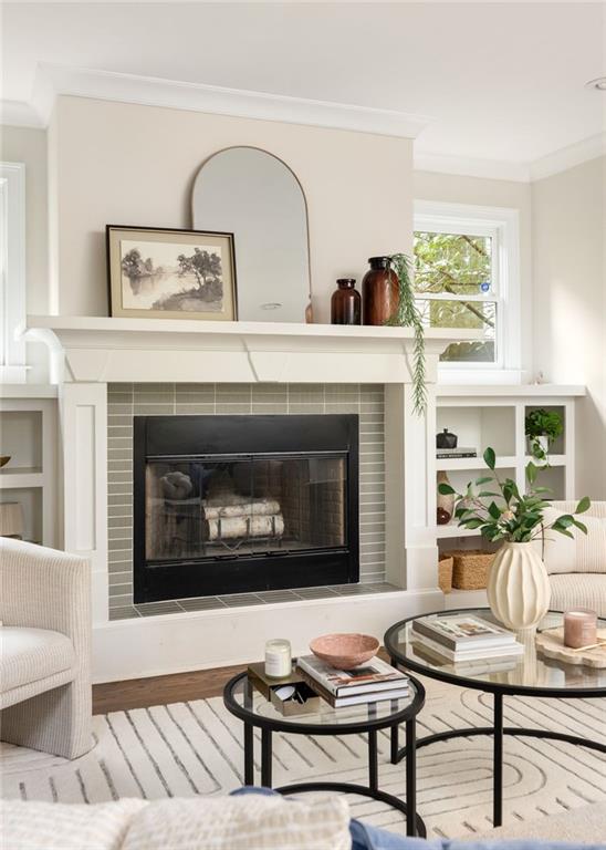 Living room with a tiled fireplace, white built-in shelves, and round coffee tables.