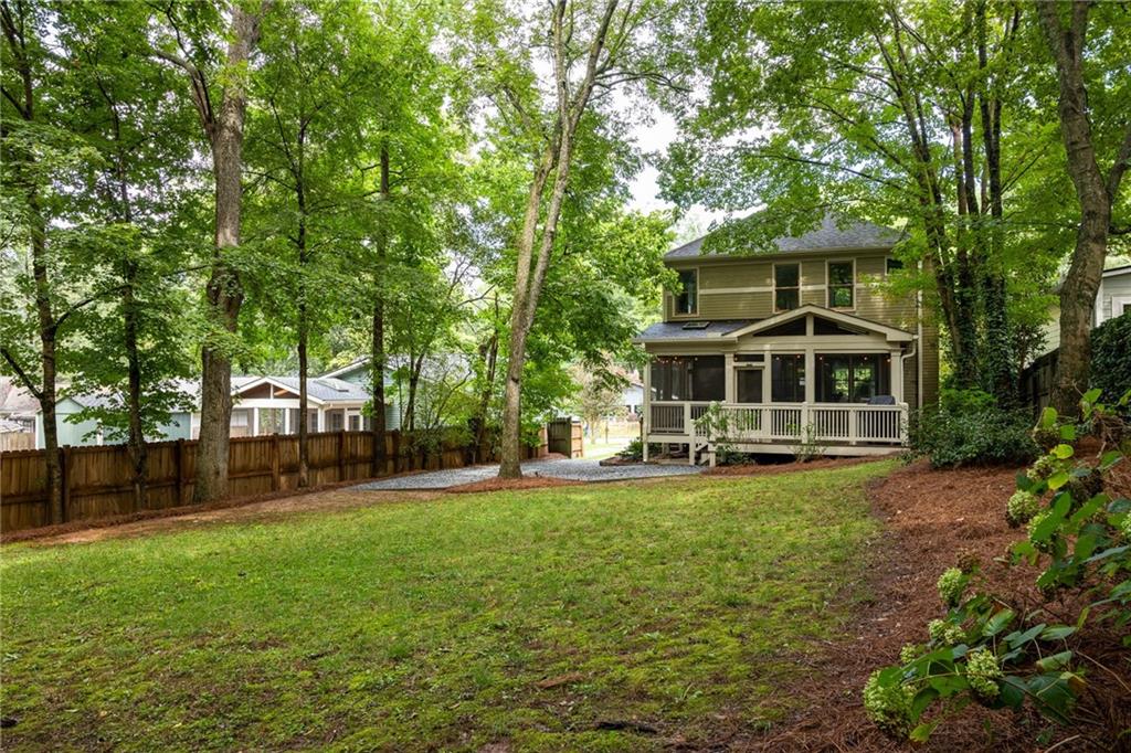 Two-story home with a covered porch at the far end of a tree-shaded backyard.