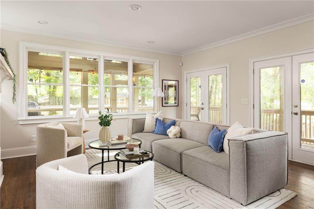 Living room with a gray sectional, cream chairs, and large windows overlooking a covered porch.