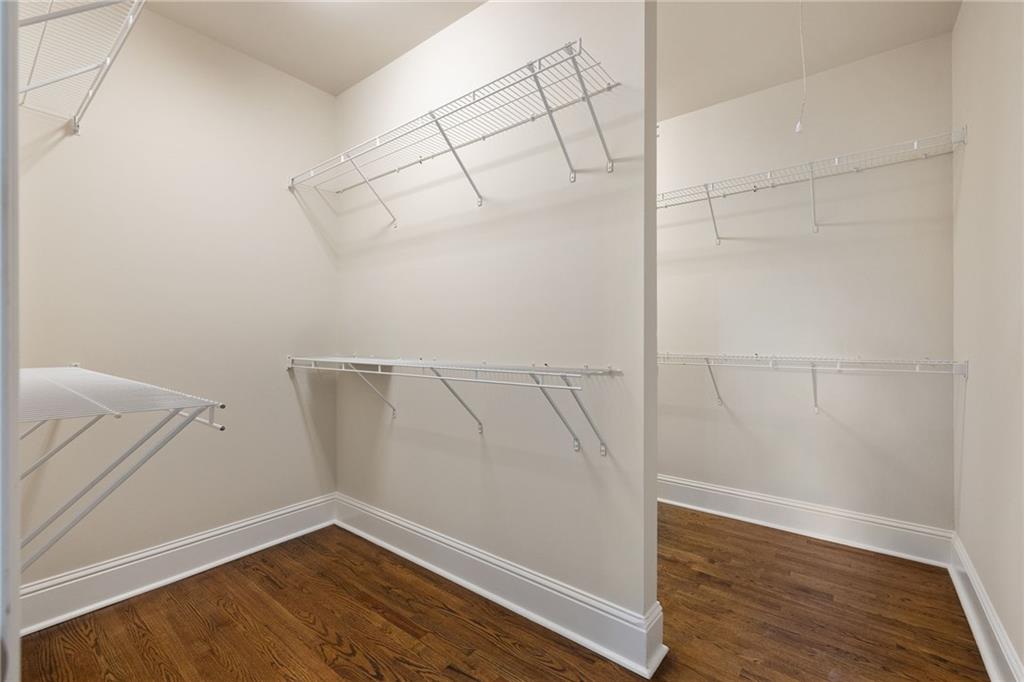 Empty walk-in closet with white wire shelving and dark hardwood floors.