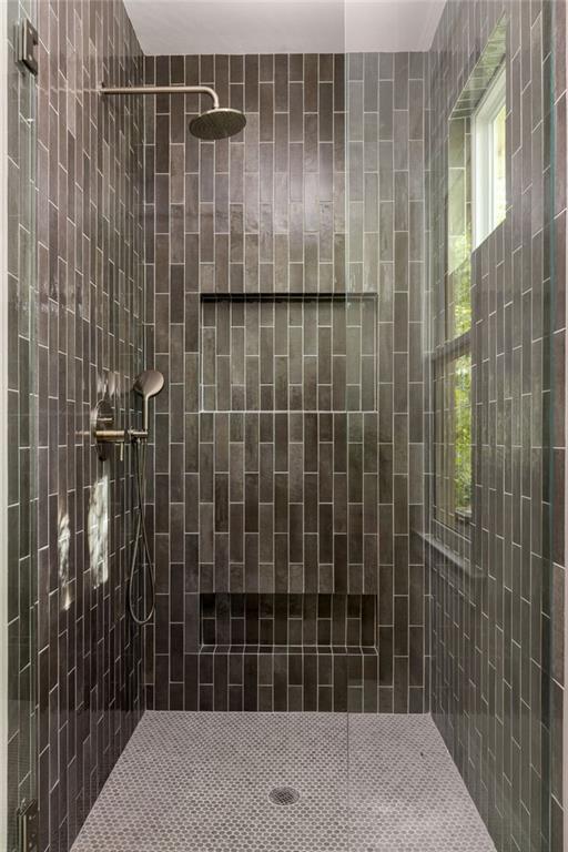 Walk-in shower with dark vertical tile, two recessed niches, and a tall window.